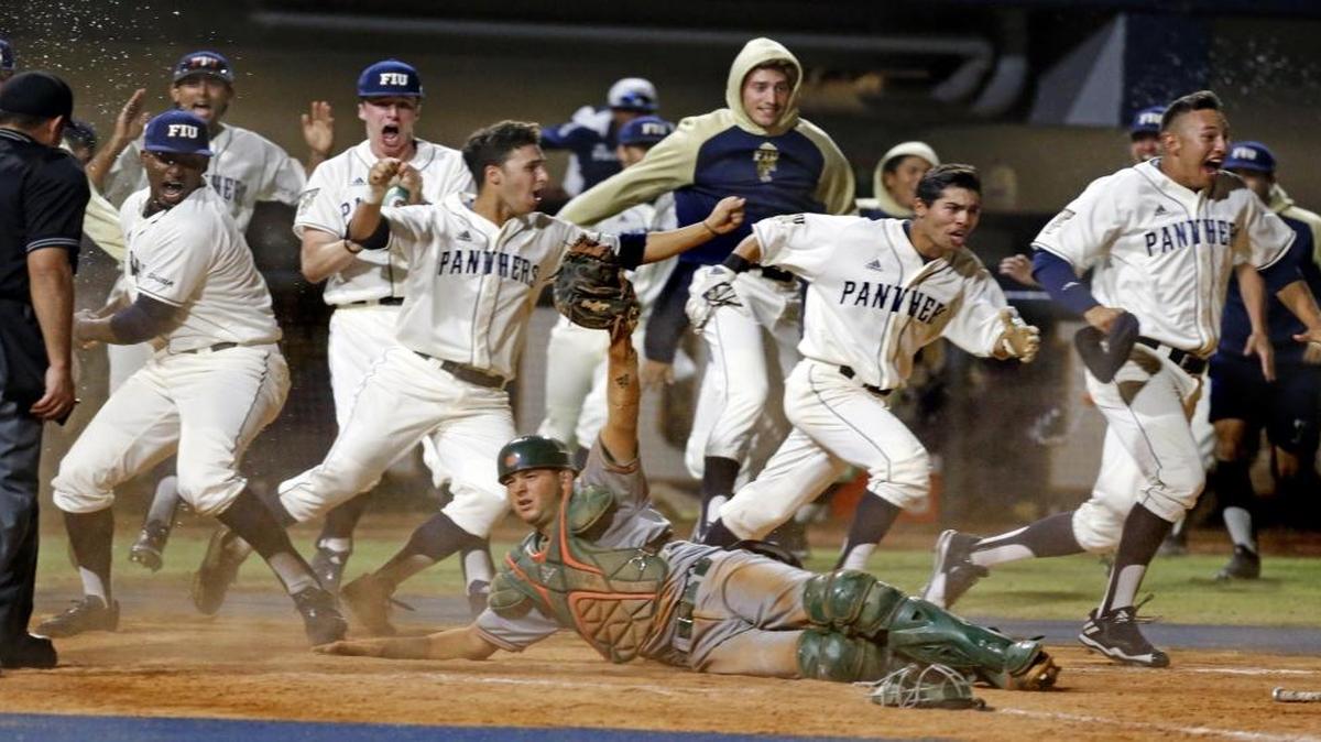 The Panthers rush the field after FIU pinch-runner Kolby Follis (14) slides home to score around Miami catcher Joe Gomez (40) in the bottom of the ninth inning to give FIU a 3-2 victory over the University of Miami. FIU's Nick Day's two-base sacrifice fly deep to center drove home Folli at FIU Baseball Stadium University Park on Wed., March 8, 2017.