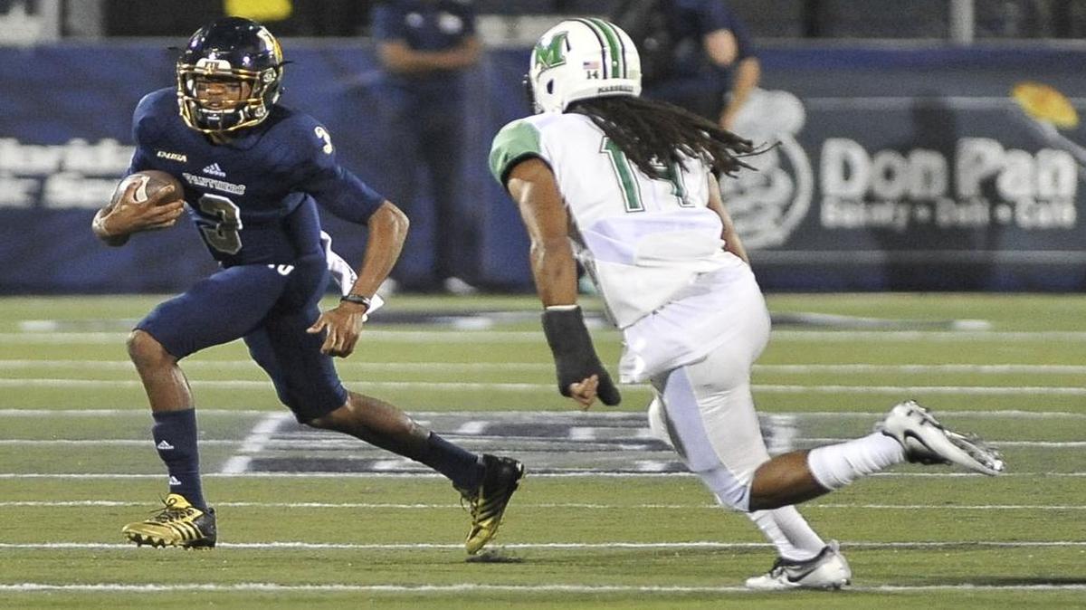 FIU quarterback Maurice Alexander, left, tries to get past Marshall’s Kendall Grant during the first half of Saturday night’s game at FIU Stadium.