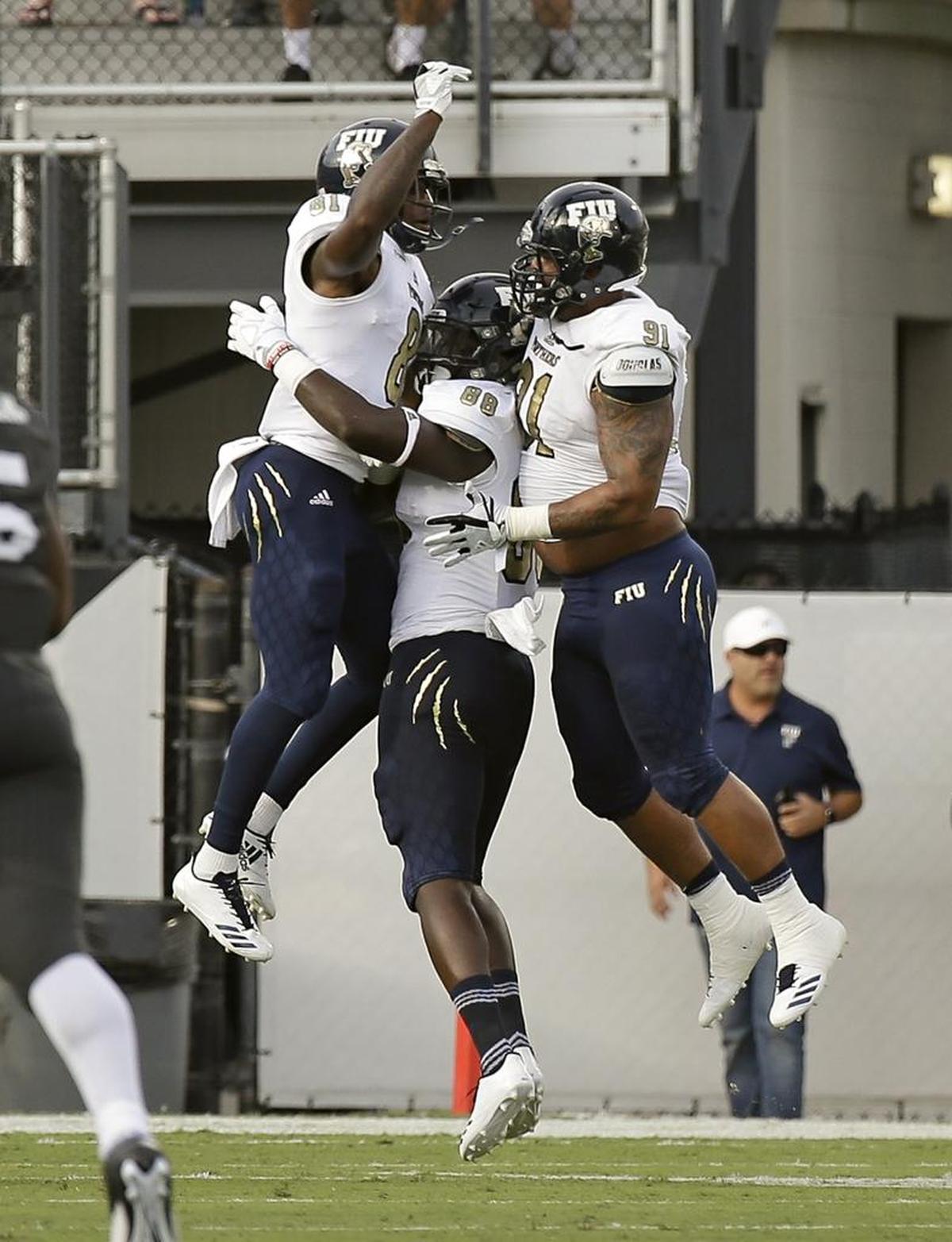 FIU senior receiver Thomas Owens, left, celebrates his 75-yard touchdown against UCF with teammates Pharoah McKever, center, and Anthony Johnson.