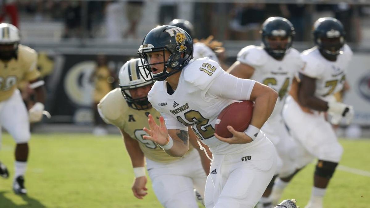 
Florida International quarterback Alex McGough (12) runs for yardage past Central Florida defensive lineman Luke Adams, left, during the first half of an NCAA college football game, Thursday, Sept. 3, 2015, in Orlando, Fla.
