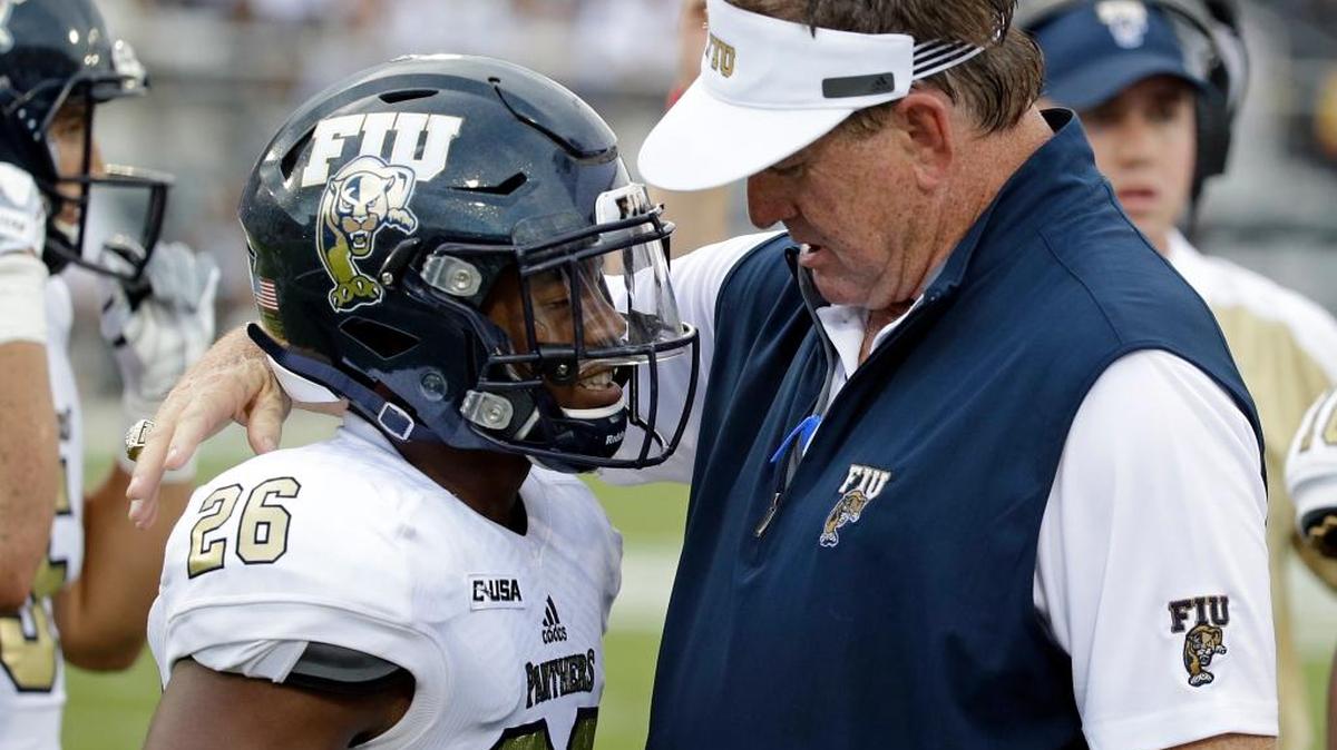 FIU coach Butch Davis congratulates safety Shermarke Spence after he intercepted a UCF pass during the first half of Thursday’s game.