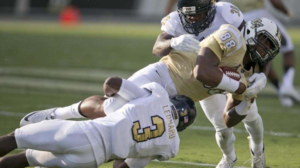 
FIU’s Richard Leonard (3) and Wilkenson Myrtil (38) tackle UCF receiver Jordan Akins in the first quarter at Bright House Networks Stadium in Orlando on Thursday, Sept. 3, 2015.
