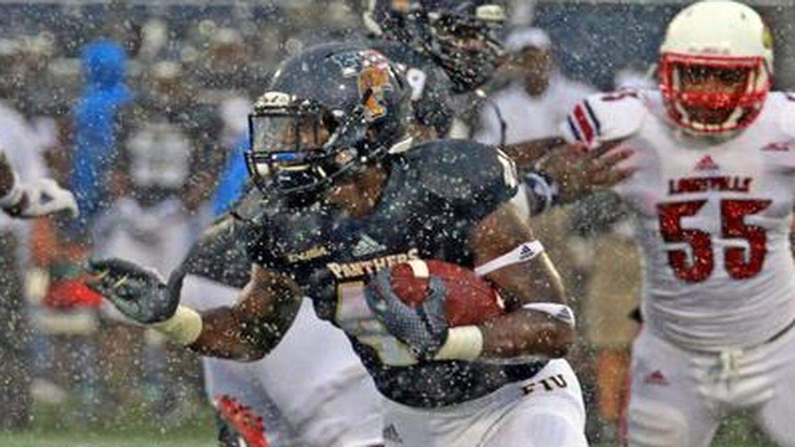 Through heavy rain:  FIU’s Anthon Samuels runs the ball in the second quarter at home against Louisville on Saturday.