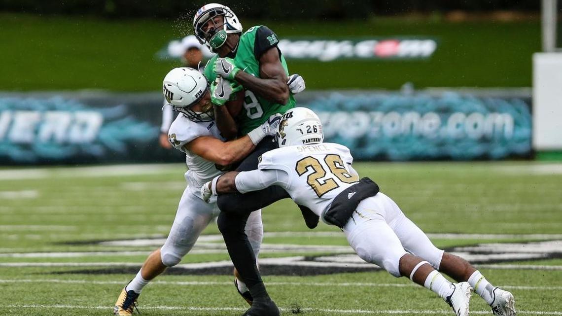 Marshall wide receiver Tyre Brady is tackled by FIU defenders Shemarke Spence (26) and Niko Gonzalez (33) after making a catch during an NCAA college football game, Saturday, Oct. 28, 2017, at Joan C. Edwards Stadium in Huntington, W.Va.