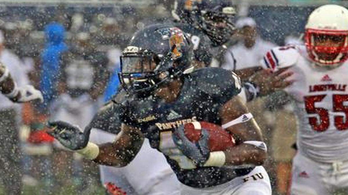 
FIU'S Anthon Samuels runs the ball in the second quarter as a heavy rain sweep through the stadium as they play Louisville at Ocean Bank Field at FIU Stadium in Miami, Florida, September 20, 2014.

