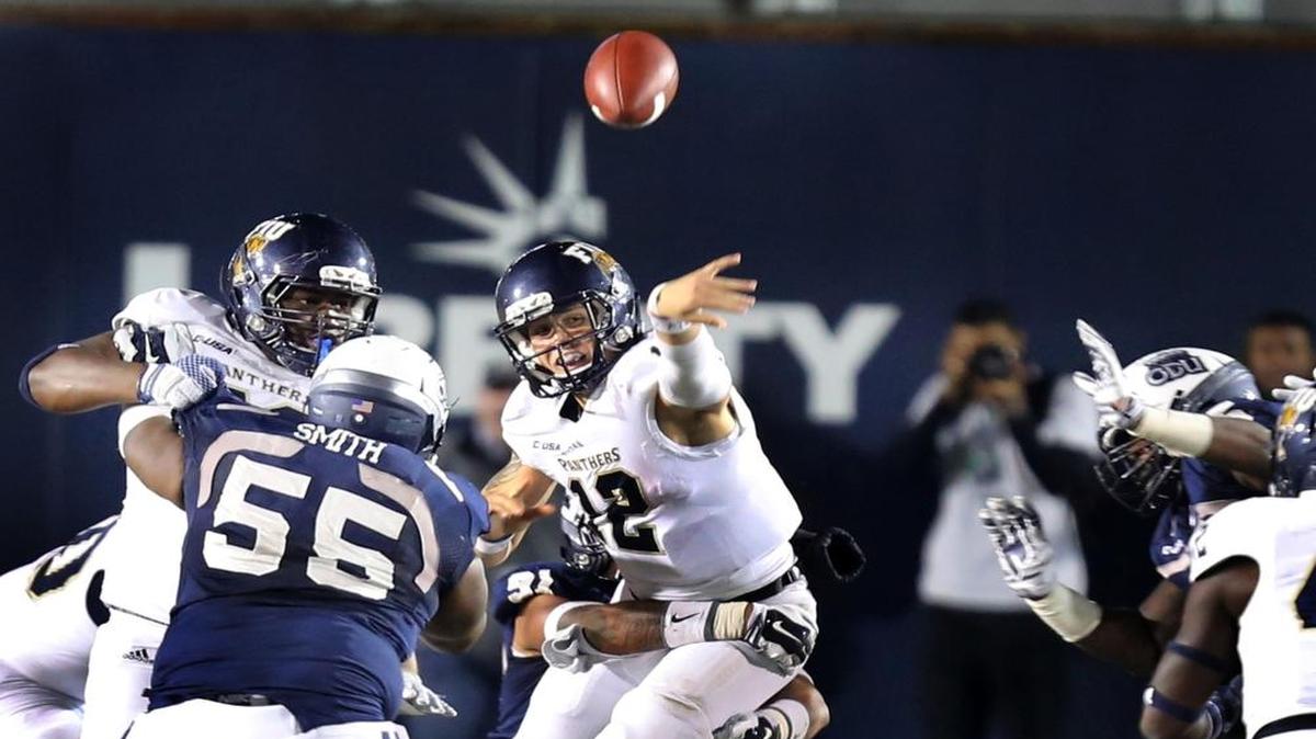 FIU quarterback Alex McGough (12) throws a left-handed pass while being pursued by Old Dominion defenders last season.