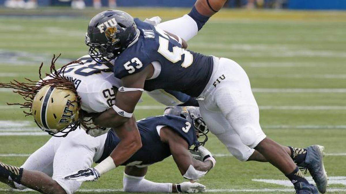 
Gang tackle: FIU’s Richard Leonard (3) and Anthony Wint (53) take down Pitt wide receiver Manasseh Garner during the football game last Saturday.
