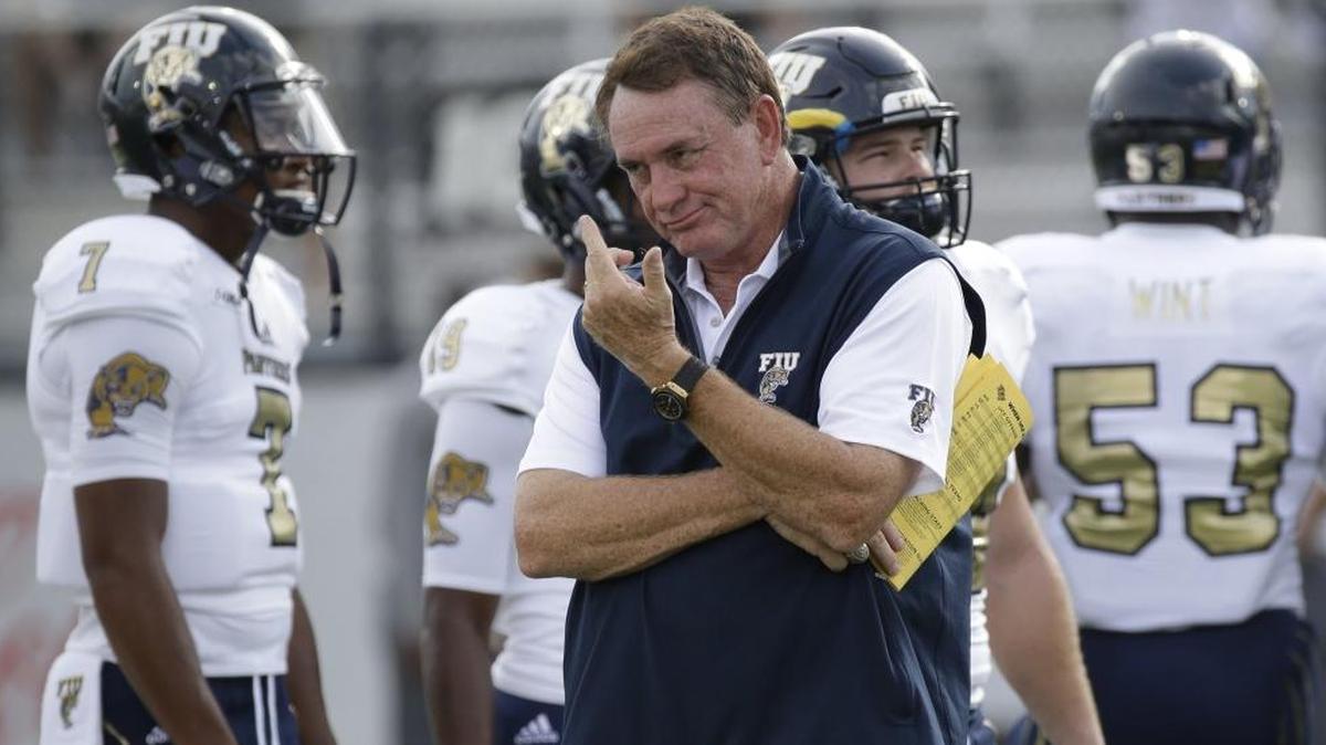 Florida International head coach Butch Davis, center, watches his players warm up before the first half of an NCAA college football game against Central Florida, Thurs., Aug. 31, 2017, in Orlando, Fla.