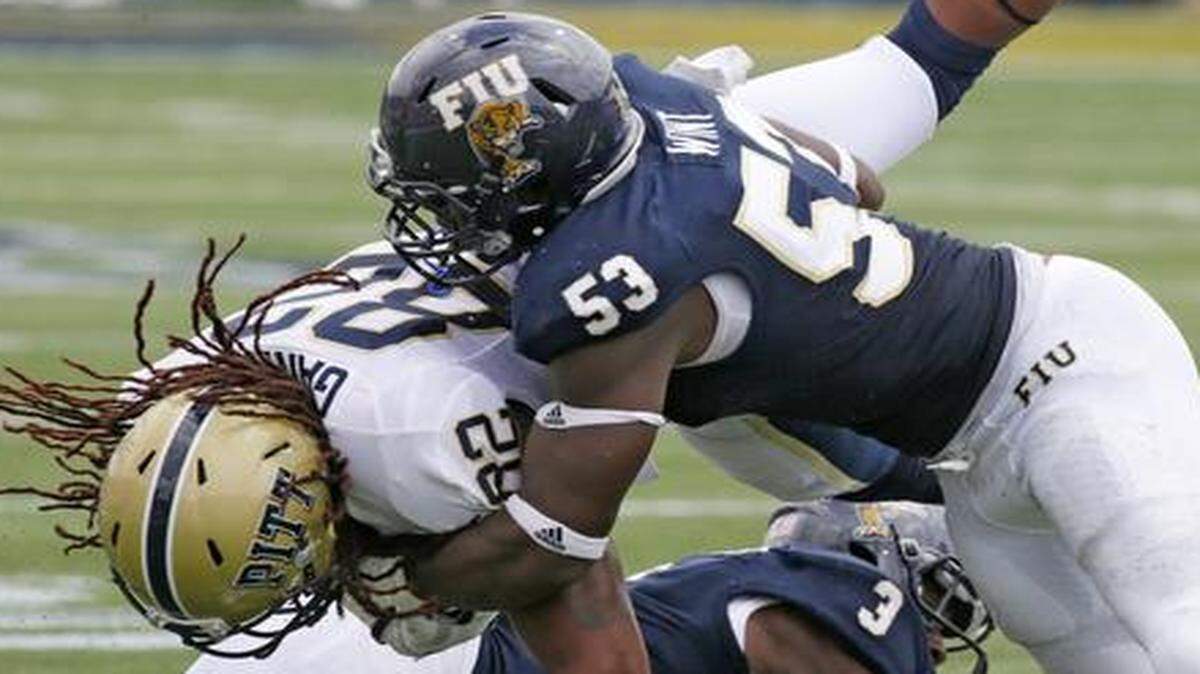 
FIU’s Anthony Wint (53) and Richard Leonard (3) take down Pitt wide receiver Manasseh Garner. 
