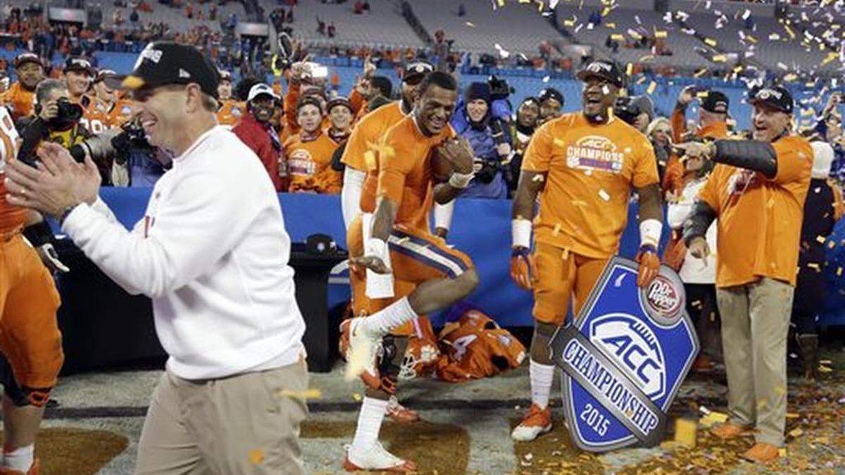 Clemson quarterback Deshaun Watson holds a football as coach Dabo Swinney celebrates after Clemson defeated North Carolina 45-37 in the Atlantic Coast Conference championship NCAA college football game in Charlotte, N.C., early Sunday, Dec. 6, 2015.