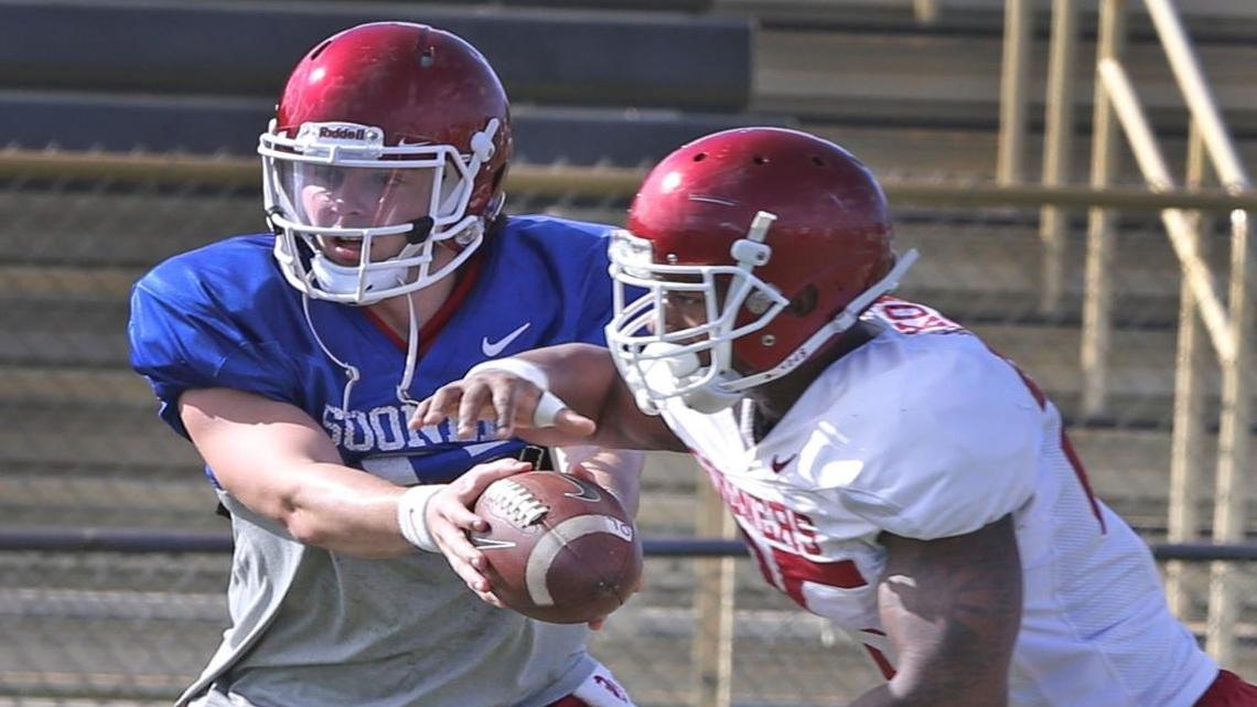 Oklahoma quarterback Baker Mayfield, left, hands the ball off during Monday’s practice at Barry University.