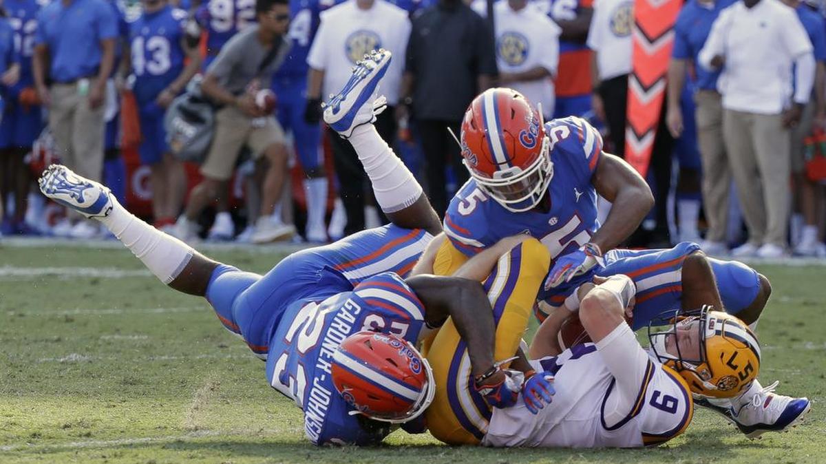 LSU quarterback Joe Burrow (9) is tackled by Florida defensive back Chauncey Gardner-Johnson (23) and defensive back CJ Henderson, right, after running for a first down during the first half of an NCAA college football game, Saturday, Oct. 6, 2018, in Gainesville, Fla.