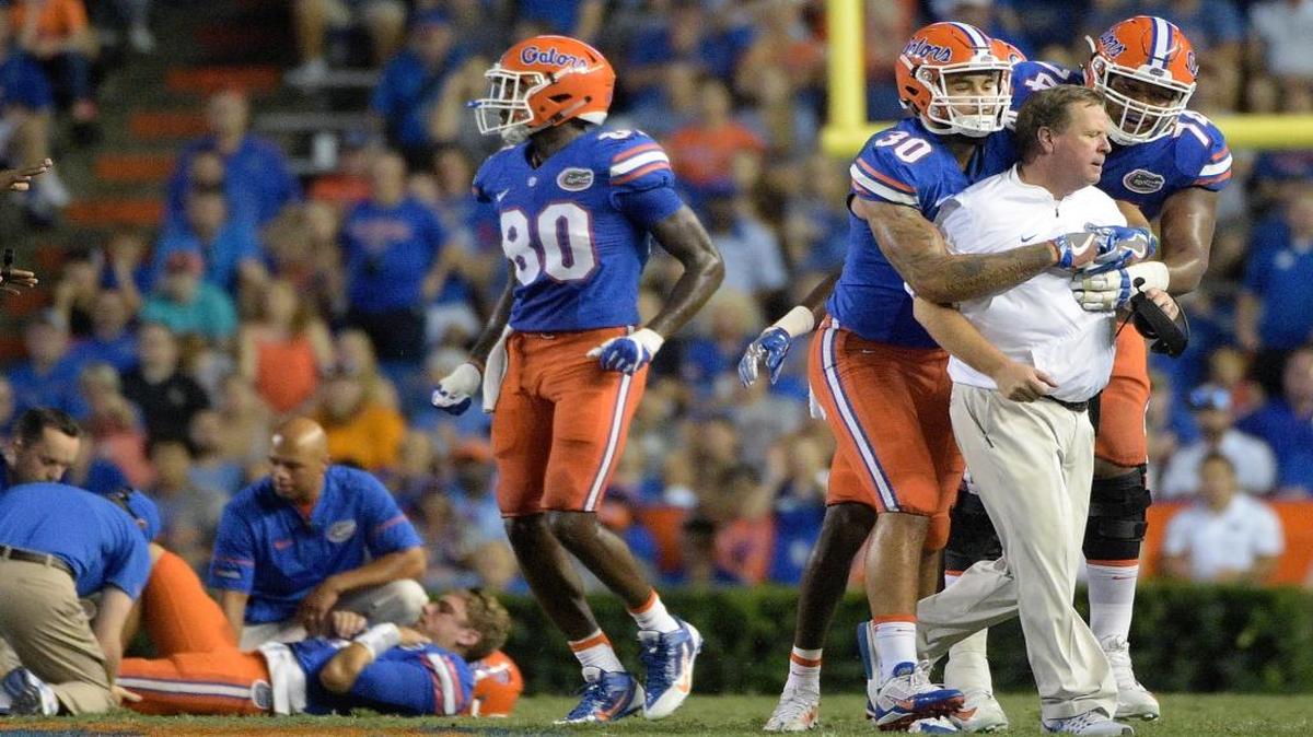 Florida coach Jim McElwain is restrained by tight end DeAndre Goolsby (30) and offensive lineman Fred Johnson (74) after McElwain showed his displeasure after quarterback Luke Del Rio, left, was knocked out of the game during the second half of an NCAA college football game against North Texas in Gainesville, Fla., Sat., Sept. 17, 2016. North Texas was penalized for roughing the passer.