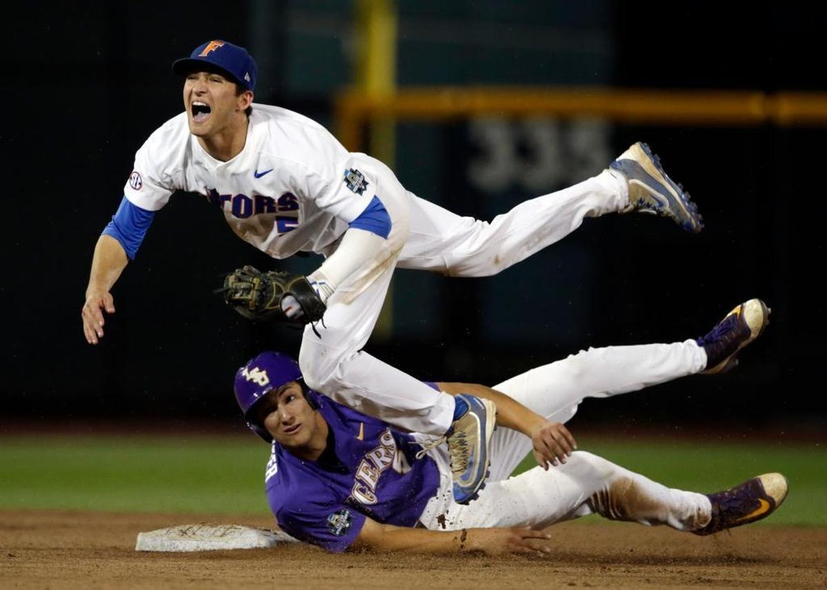 Florida shortstop Dalton Guthrie, top, falls after being hit by LSU's Jake Slaughter at second base on a double play hit by Michael Papierski during the seventh inning in Game 2 of the NCAA College World Series baseball finals in Omaha, Neb., Tues., June 27, 2017. Papierski was out at first.