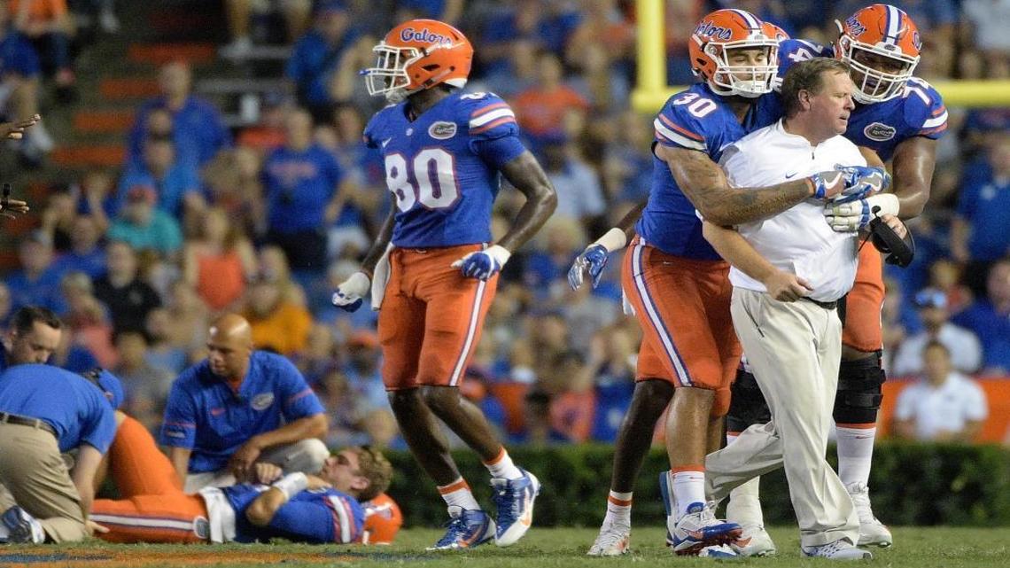 Florida coach Jim McElwain is restrained by tight end DeAndre Goolsby (30) and offensive lineman Fred Johnson (74) when McElwain showed his displeasure after quarterback Luke Del Rio, left, was knocked out of the game during the second half Saturday night against North Texas in Gainesville.