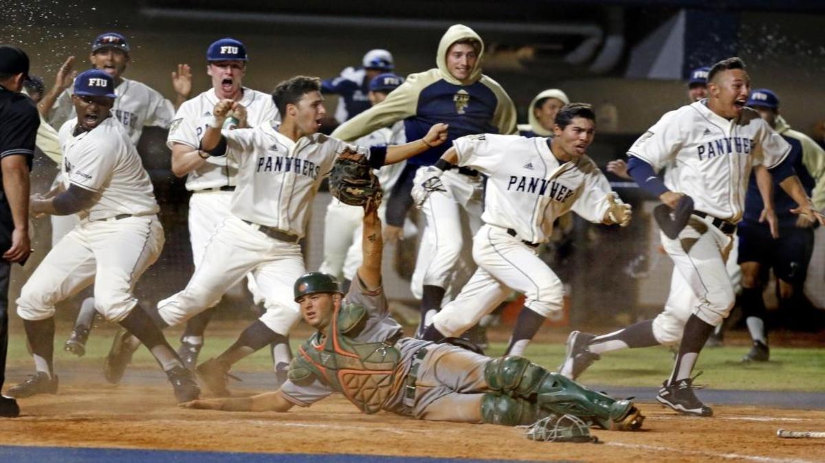 The Panthers rush the field after FIU pinch-runner Kolby Follis (14) slides home to score around Miami catcher Joe Gomez (40) in the bottom of the ninth inning to give FIU a 3-2 victory over the University of Miami. FIU's Nick Day's two-base sacrifice fly deep to center drove home Folli at FIU Baseball Stadium University Park on Wed., March 8, 2017.