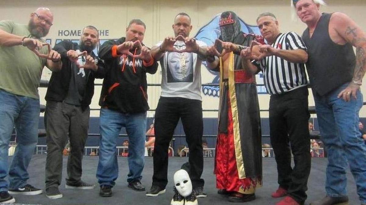 In the ring -- centered around the mask and wrestling boots of The Blackheart Dave Johnson for the 10-bell salute at a CCW show -- are (from left) Shawn Murphy, Joey Machete, Sean Allen, MVP, Kahagas, Randy Eller and Wet Willy. MVP, a WWE alum, said a few words, and the locker-room lined up outside the squared circle at the show opening on Saturday, Dec. 9 at the Coral Springs Charter School Gym.