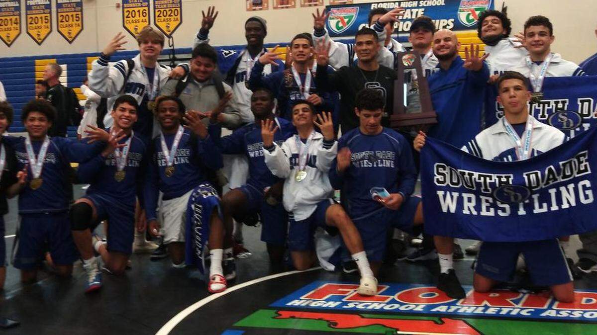 South Dade gathers together with its fourth FHSAA Team Duals Class 3A wrestling state championship trophy on Saturday at Osceola High School in Kissimmee.