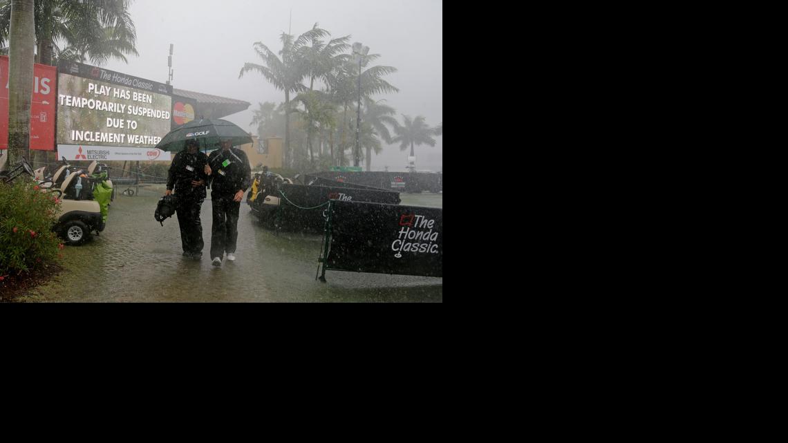 
A TV crew heads to the clubhouse for cover because of heavy rain at the Honda Classic.
