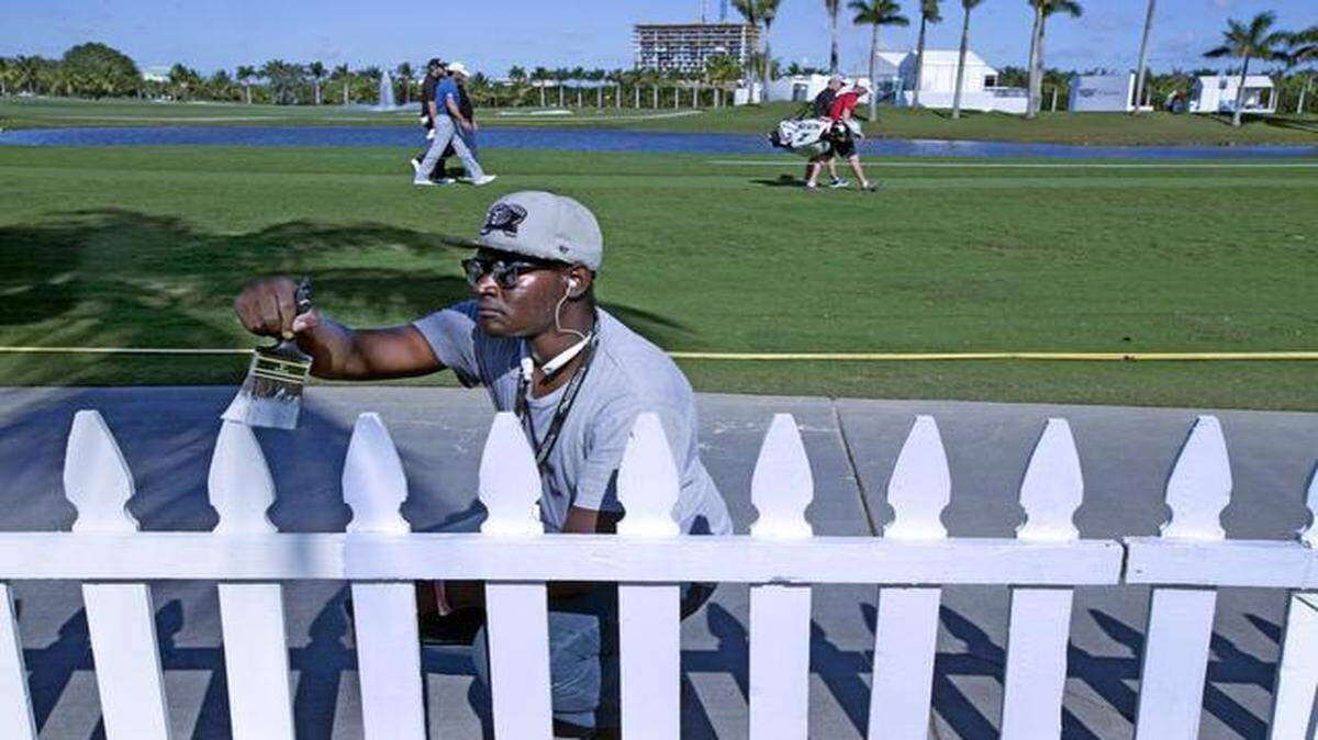 
Mario Austin paints the white picket fence along the 18th fairway on the Blue Monster course as ground crews prepare for the Cadillac Championship at the Trump National Doral.
