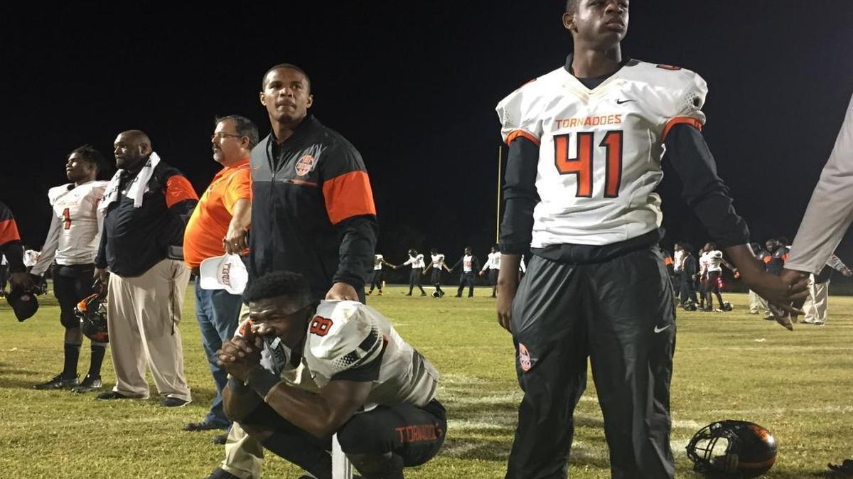 Booker T. Washington assistant coach Brandon Harris consoles linebacker Jaquan Beaver after the Tornadoes lost to Cocoa 24-21 on Friday in the Class 4A state semifinals. Booker T. has won four consecutive state titles and made five trips in a row to the state final.