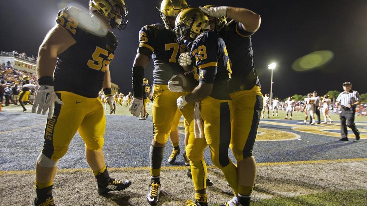 
St. Thomas Aquinas teammates surround Devonta’e Henry-Cole after he scores in the first quarter against visiting Booker T. Washington on Friday, August 28, 2015.
