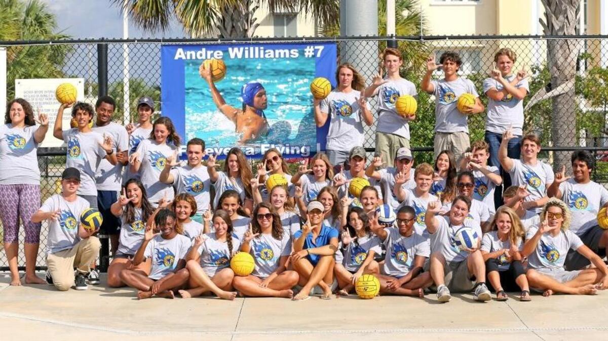 The Fort Lauderdale water polo teams gather around a poster of Andre Williams, a teammate who recently passed away in a motorcycle accident, for a portrait at the school’s pool as the Flying L’s prepare for the season.