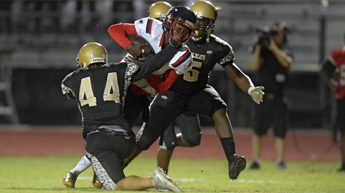 Miramar's Steven Williams is tackled by Western's Dylan Litsenberger and Jordan Chambers during the first half of their game, Fri., Oct. 27, 2017.