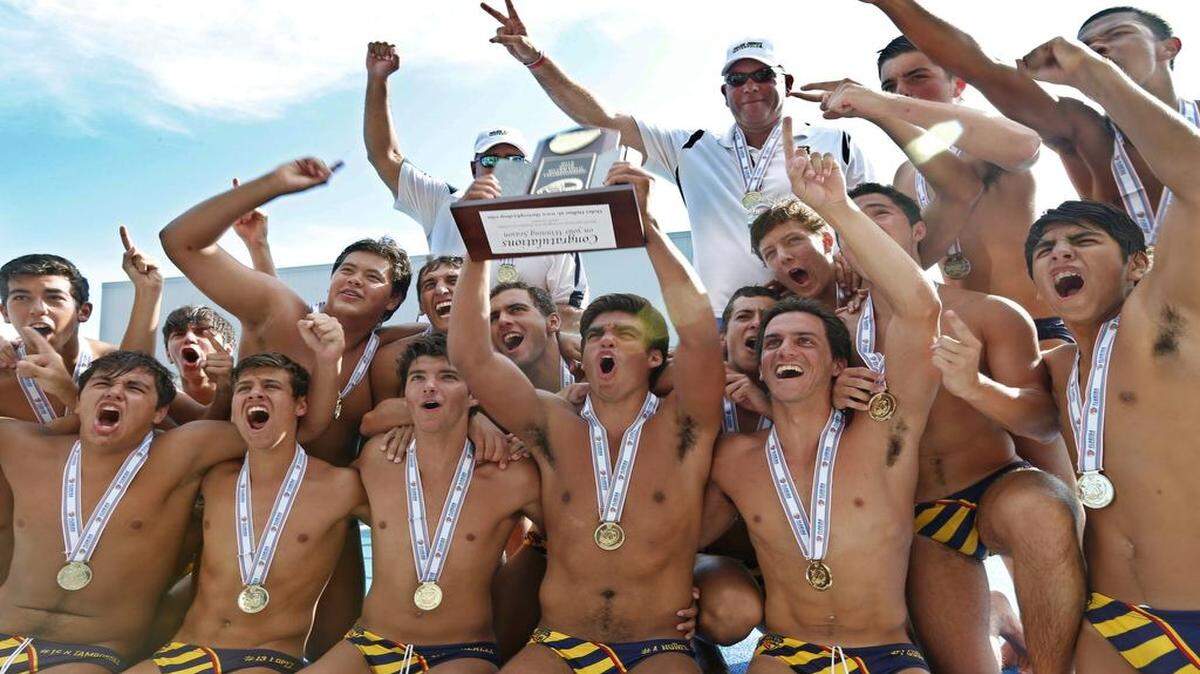 
Pool party: Belen Jesuit’s Santiago Nunez holds up the FHSAA championship trophy as he celebrates with the team after defeating St. Thomas Aquinas.

