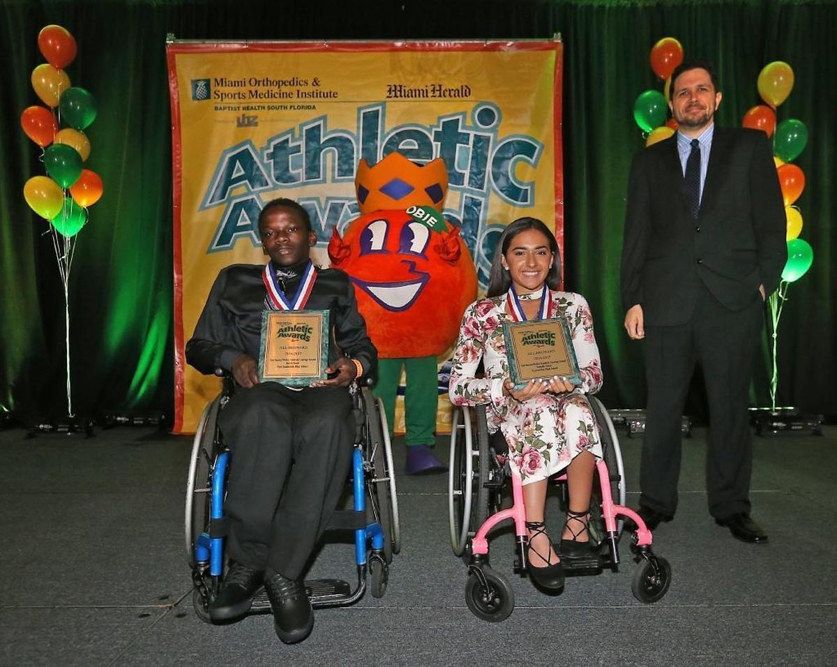 Herald Sportswriter Andre Fernandez (right) presents the Leo Suarez/Walter Krietsch Courage Award to Fort Lauderdale High's Darrel Bouie Jr. and Cypress Bay's Isabella Matos at the Miami Herald Broward Athletic Awards banquet at the Signature Grand in Davie on Thurs., May 25, 2017.