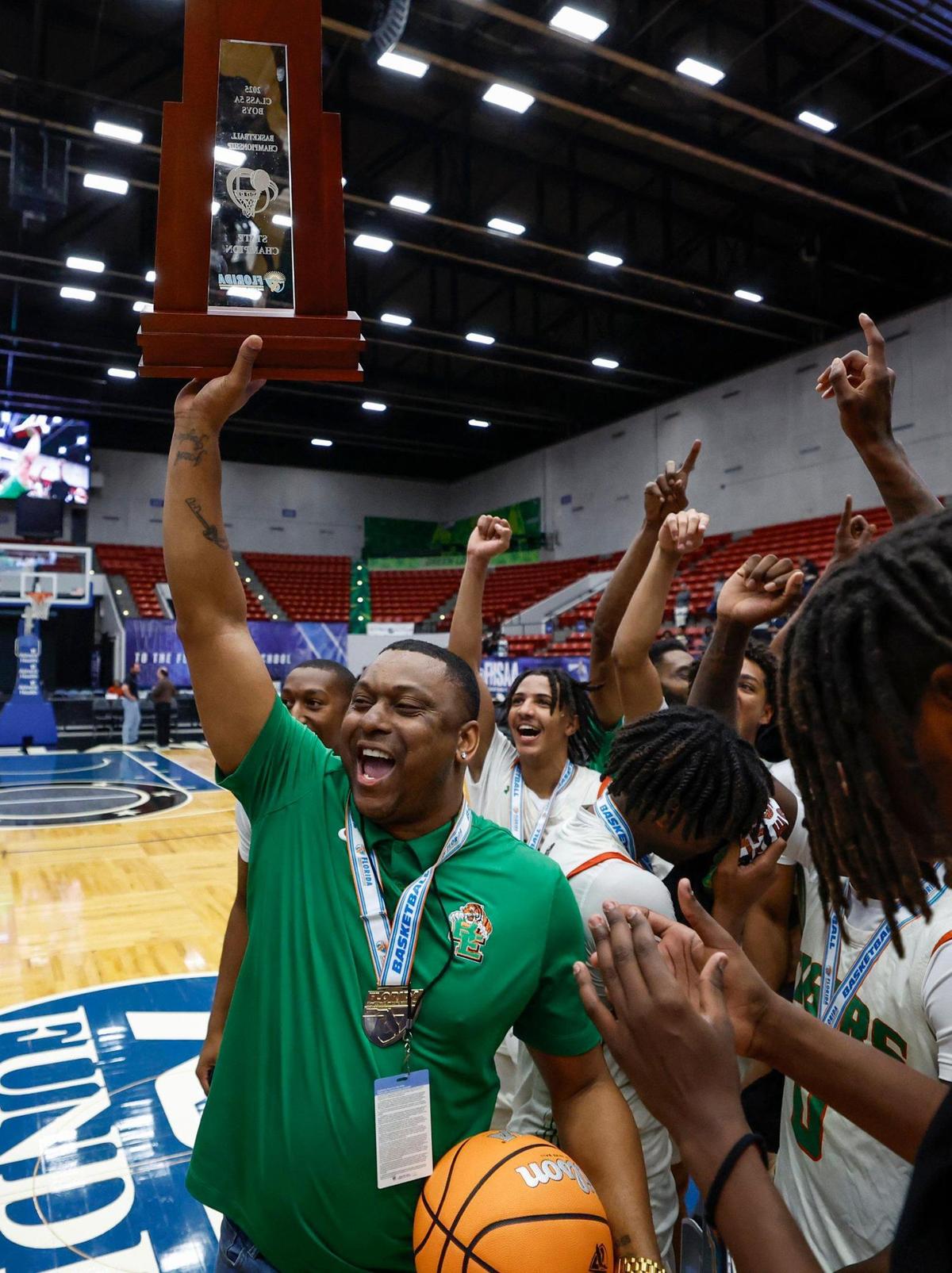 Blanche Ely Tigers’ head coach J.R. McNabb raises the championship trophy after defeating Ponte Vedra in the FHSAA Class 5A Final for Boys High School Basketball State Championship at the RP Funding Center in Lakeland, Florida on Friday, March 7, 2025.