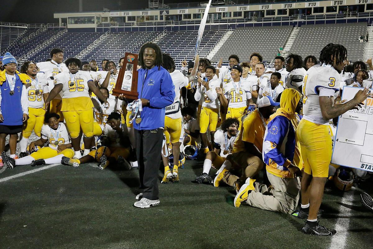 Northwestern Bulls head coach Teddy Bridgewater holds the state championship trophy after his team won the Class 3A state final against the Jacksonville Raines Vikings on Saturday, December 14, 2024 at Pitbull Stadium in Miami.