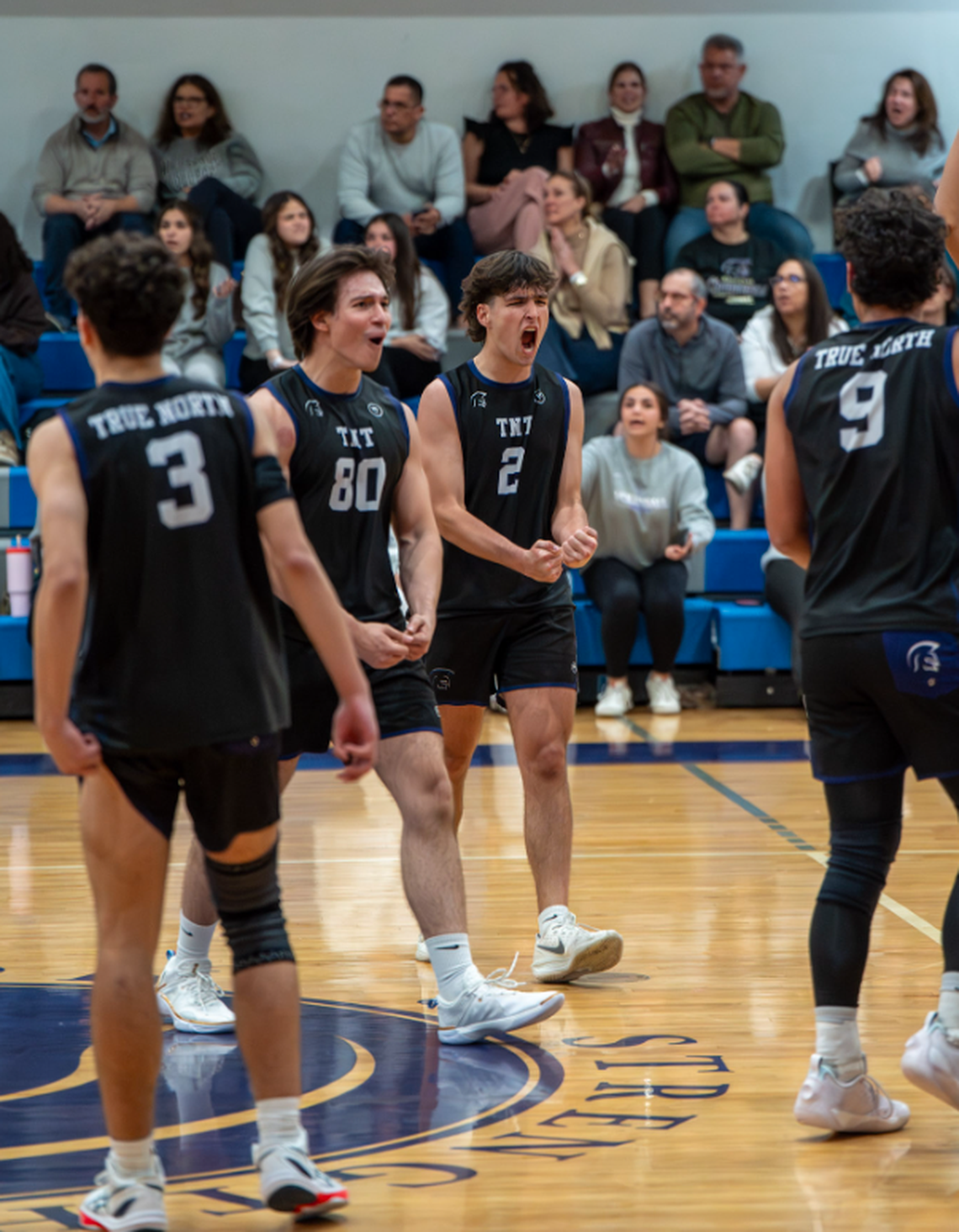Aisar Hernandez celebrates with teammates as True North boys’ volleyball defeats Southwest.
