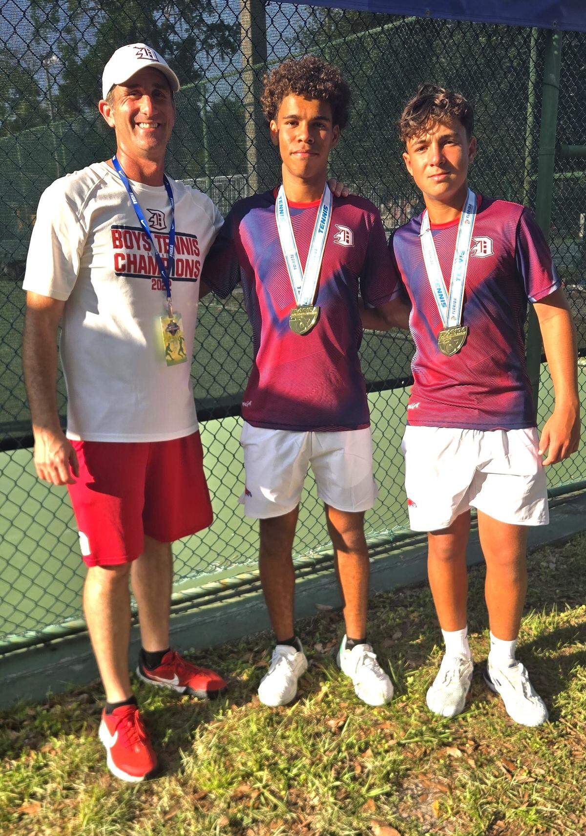Doral Academy tennis coach Justin Puppo with state champions Samuel Rosales and Vincenzo Palmiotto.