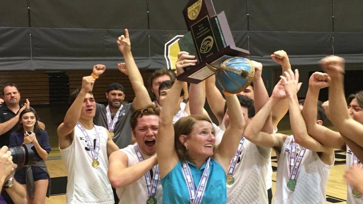 Archbishop McCarthy coach Karen Frank raises the state championship trophy as she and her players celebrate the school’s first state championship in boys’ volleyball.