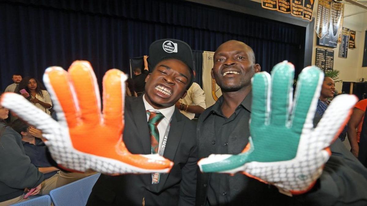 St. Thomas Aquinas' Sam Bruce Jr. flashes the U with his father, Sam Bruce, after committing to the University of Miami on National Signing Day on Feb. 3, 2016.