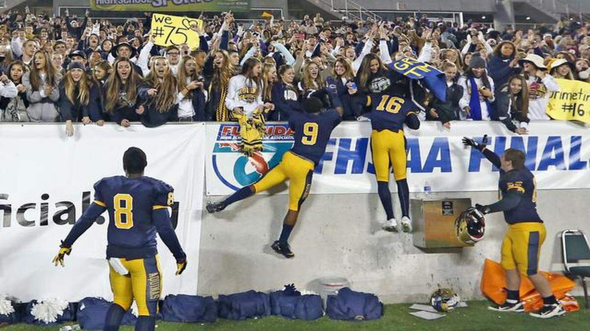 
St Thomas Aquinas players jump into the stands after defeating Osceola in the Class 7A Boys Football Championship at the Citrus Bowl in Orlando, Florida, Dec. 12, 2014.
