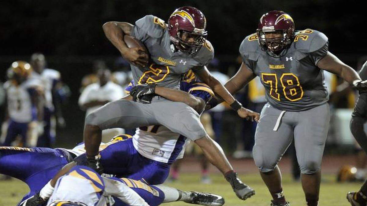 
Hallandale running back Taj McGowan tries to jump over the line while being held by Boynton Beach defensive end Quinton Wilcher during the first half, Friday, Oct. 31, 2014.
