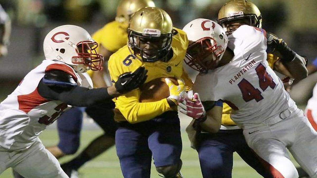 
St. Thomas Aquinas wide receiver Samuel Bruce, center, breaks through two Plantation defenders during their football game Friday, Oct. 31, 2014, at St. Thomas High School in Fort Lauderdale.
