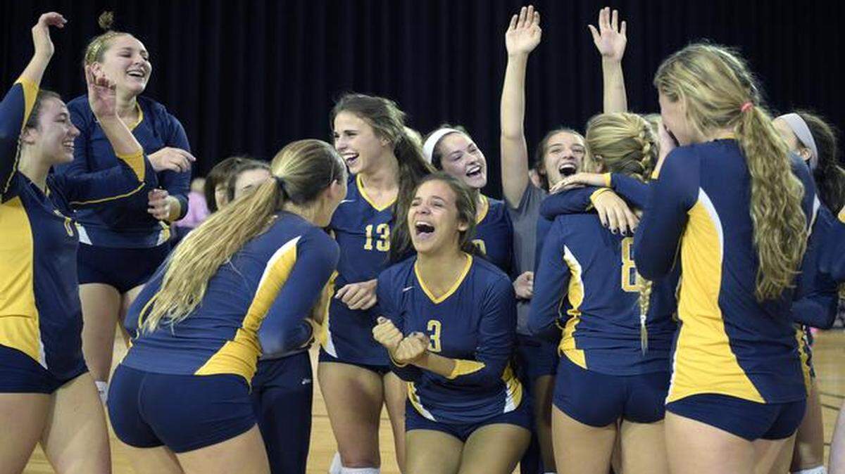 
The final hurdle: Aquinas players celebrate after their win, which followed three consecutive trips to the Final Four falling short for the Raiders. 
