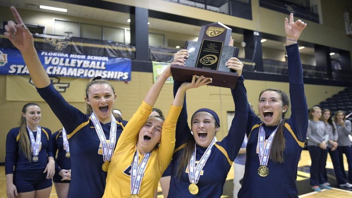 St. Thomas Aquinas players celebrate with the championship trophy after their win over Plant in the high school FHSAA Class 7A State Volleyball Finals Championship game in Orlando, Fla., Saturday, Nov. 14, 2015.