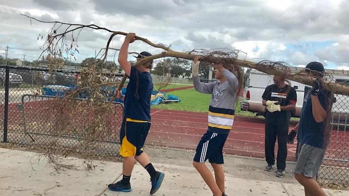 St. Thomas Aquinas baseball players help clear some tree branches that littered neighborhood rival Nova’s field after Hurricane Irma. The two longtime rivals helped each other during the cleanup process this week.