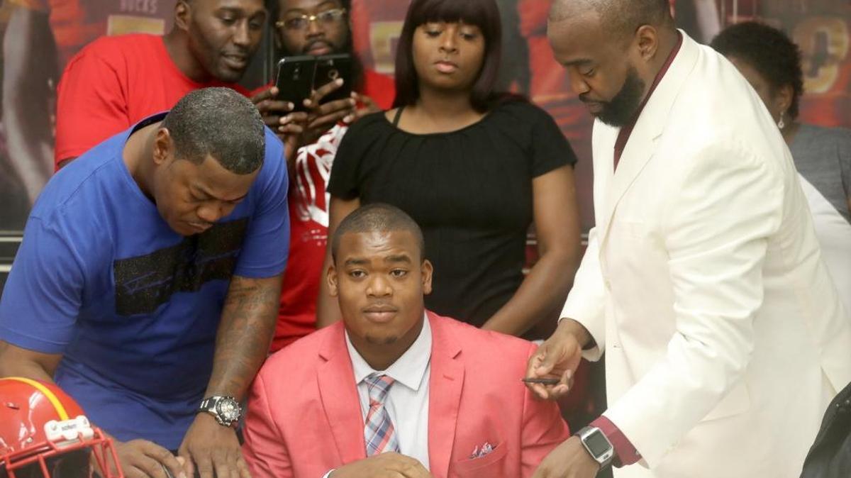 Rosendo Louis signs to play for the University of South Carolina during the Deerfield Beach football early signing day ceremony.