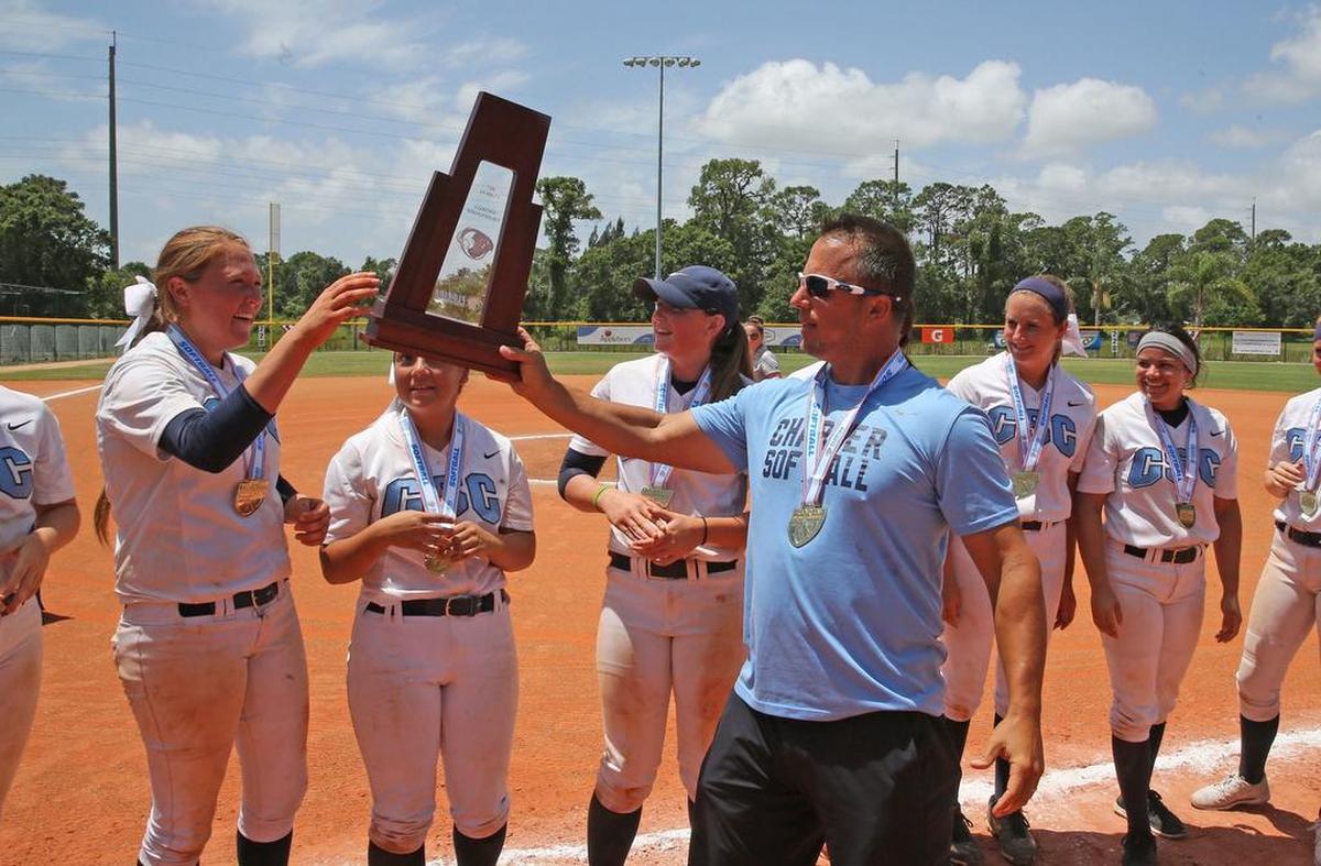 Coral Springs Charter coach Mark Montimurro hands the trophy to Ally Muraskin after defeating Eustis-Hardee in the FHSAA 5A Girl’s Softball State Finals in Vero Beach, Fla., Saturday, May 20, 2017.