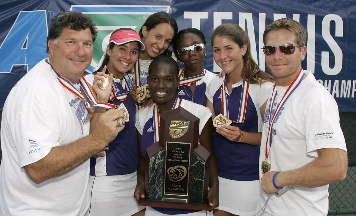 In this file photo, left to right, Dr. Krop HS tennis coach Coach Michael Kypriss, Taylor Dubins, Maria Roman, top, Deon Miller, holding trophy, Brittany Henry, Brittany Dubins and Coach Damon Hollenback show off their trophy after winning the FHSAA Class 4A State Tennis Finals in Altamonte Springs, Florida on Thursday, April, 26, 2007.