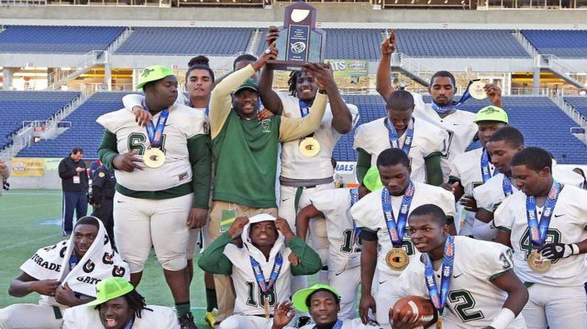 
Miami Central High School head coach Roland Smith holds the trophy with players after defeating Armwood High School in the 2014 Class 6A Boys Football Championship at the Citrus Bowl in Orlando on Dec. 13, 2014.
