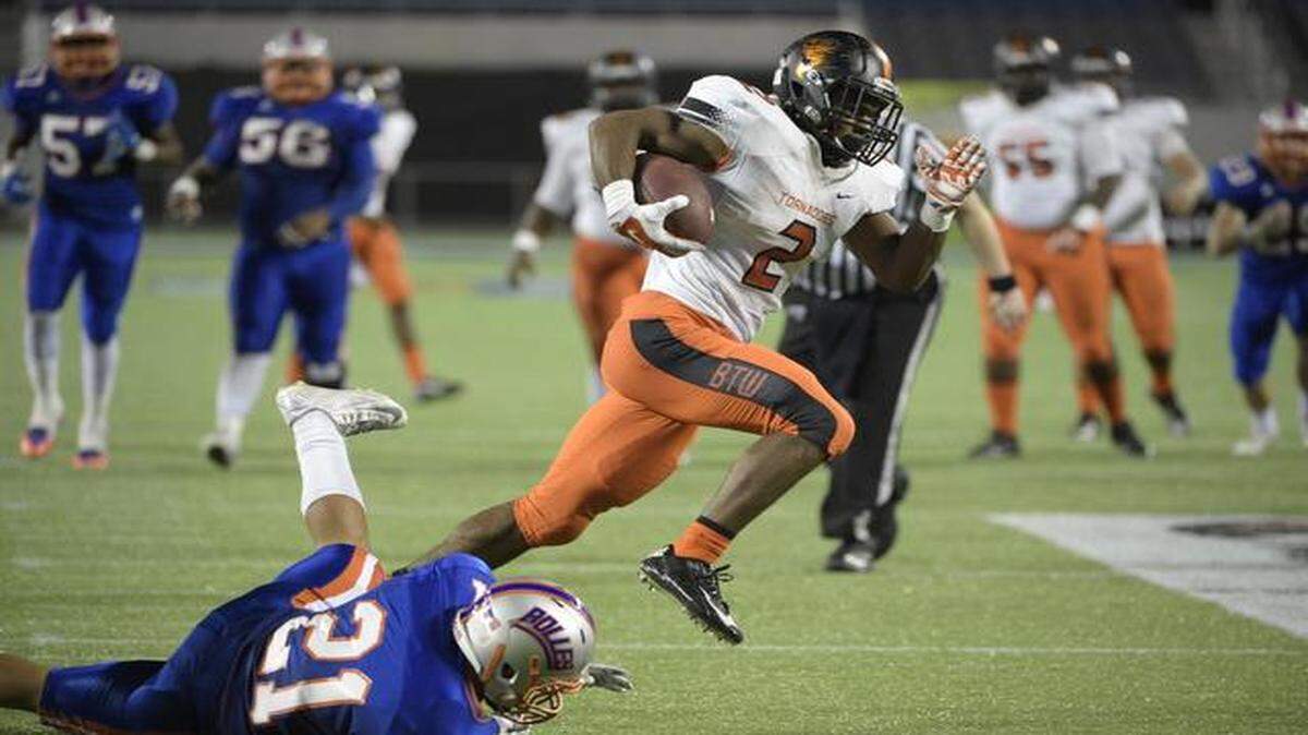 
Booker T. Washington running back Mark Walton (2) runs over Bolles defensive back T.J. Floyd (21), after catching a pass, on his way to the end zone for a touchdown during the second half of an FHSAA State Championsip football game in Orlando, Fla., Saturday, Dec. 6, 2014.

