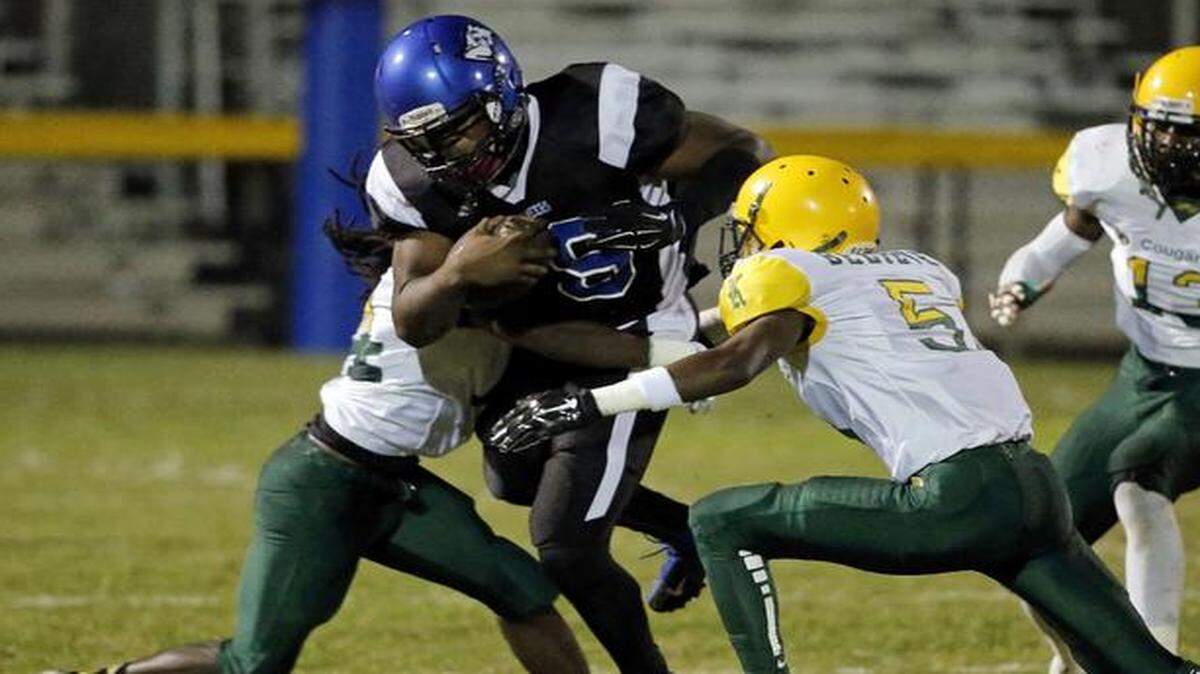 
South Dade’s P.J. Coats (19) is tackled by Killian’s Alonzo Williams (14) and Juwan Horn (5) in Homestead on Friday, Oct. 24, 2014. Killian kept the defending Class 8A champion Bucs from returning to the playoffs.

