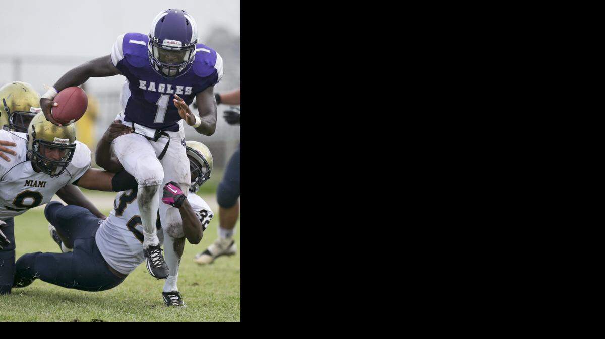 
Southwest High's quarterback Deundre Pickett-White eludes Miami High defenders as Southwest Miami High School hosts Miami Senior High at Southwest High on Friday, Sept. 26, 2014.
