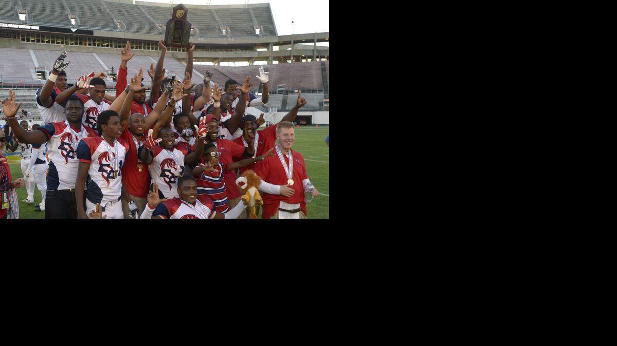 
Champagnat coaches and players hold the championship trophy after beating Victory Christian to win the FHSAA Football Class 2A Finals in Orlando on Dec. 6, 2013. 
